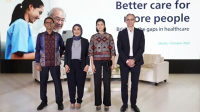 Four speakers on stage at a Philips healthcare event themed better care for more people