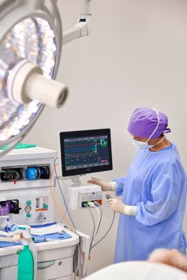 Clinician in operating room using Philips patient monitoring system beside patient