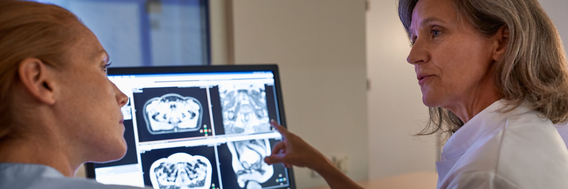 Physician pointing to scan on monitor and speaking to technician