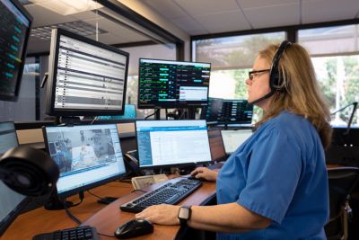 Clinician in a virtual ICU command center monitoring patients on multiple screens