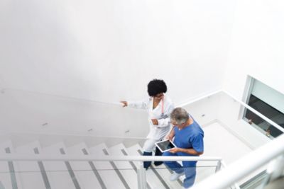 Clinicians walking up hospital stairs while reviewing information on a tablet