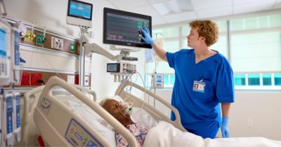 Nurse monitoring critical care patient using Philips IntelliVue system