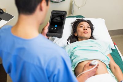 Clinician performing abdominal scan using Philips Lumify ultrasound device on patient