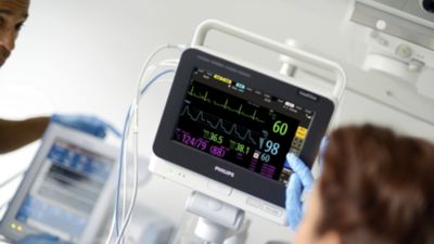 Healthcare professional reviewing vital signs on bedside patient monitor
