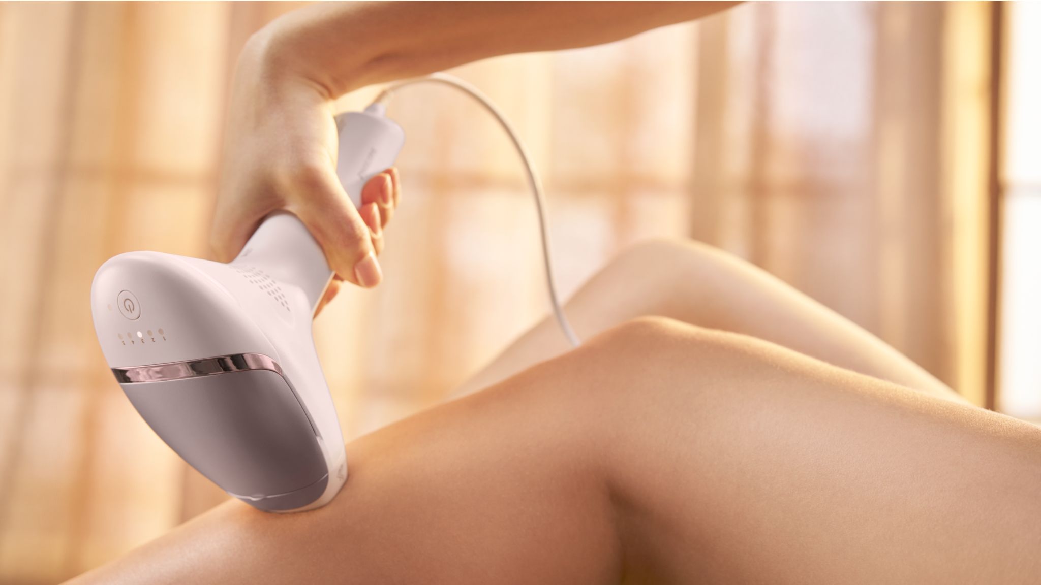 A woman using a grey Philips IPL Lumea machine on her legs.