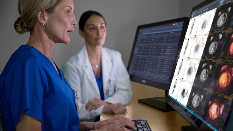 Due radiologi che interagiscono davanti a due schermi