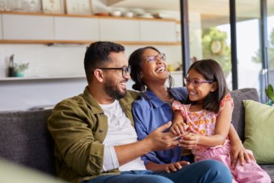 Family sitting together on sofa smiling at home