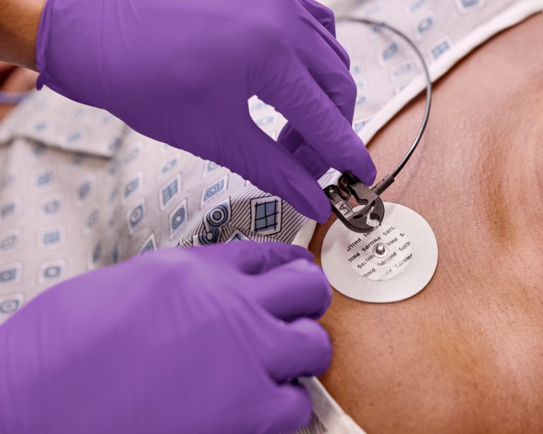 Electrode being placed on patient wearing capnography tubing, physician holding ECG cables