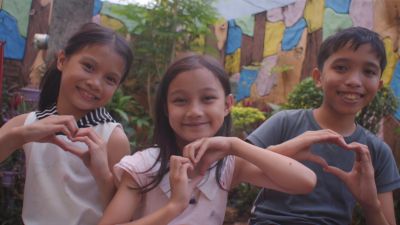 Niños haciendo formas de corazón con las manos en un entorno comunitario