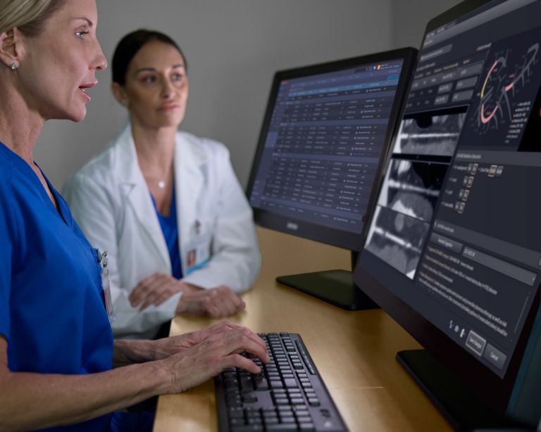 doctor and technician looking at two monitors