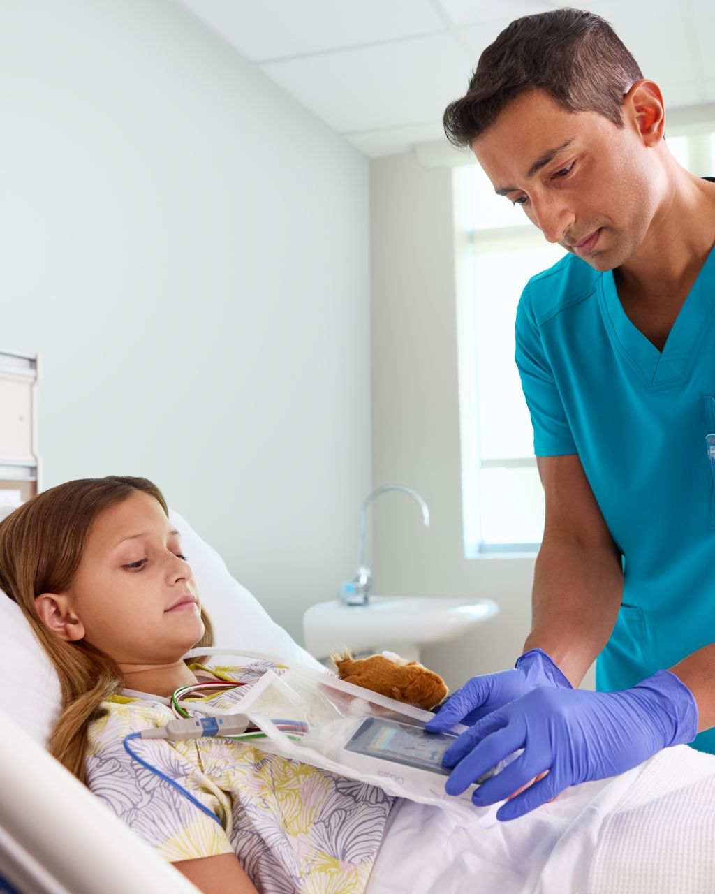 pediatric patient in a hospital bed with a clinician looking at the TM 5500