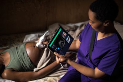 Midwife performing portable ultrasound examination on pregnant woman at home

