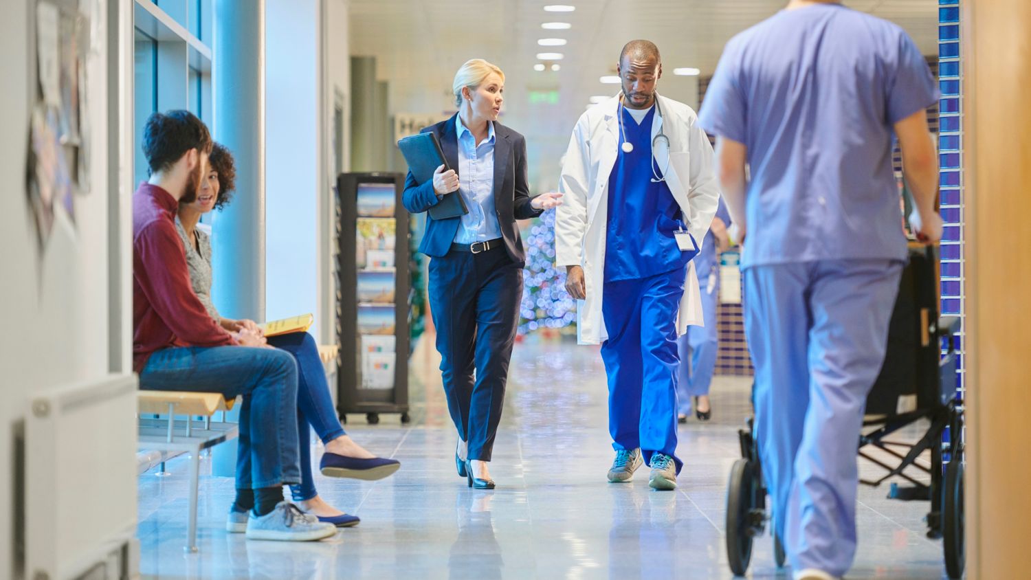 woman in suite walking down hallway speaking with doctor