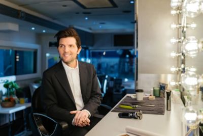Adam Scott seated at dressing room table with Philips Norelco grooming products