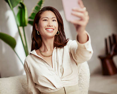 A woman smiling and taking a selfie.