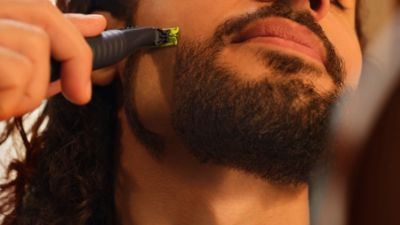 Gros plan sur un homme qui se rase la barbe avec le Philips OneBlade.