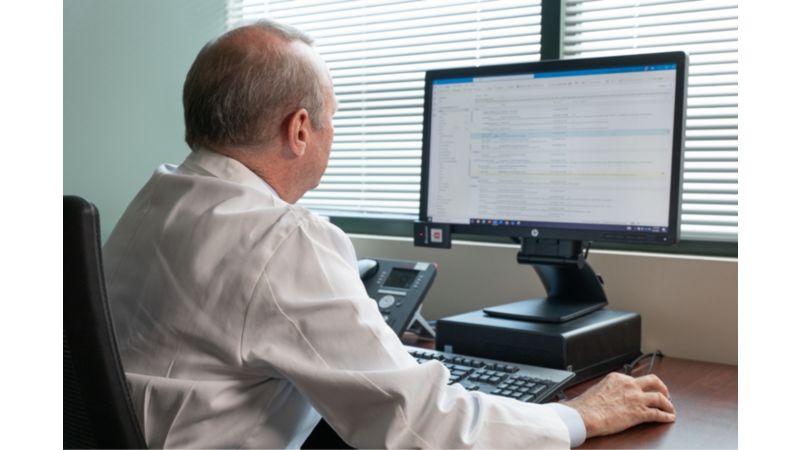 A doctor sitting at a desk looking at a computer screen