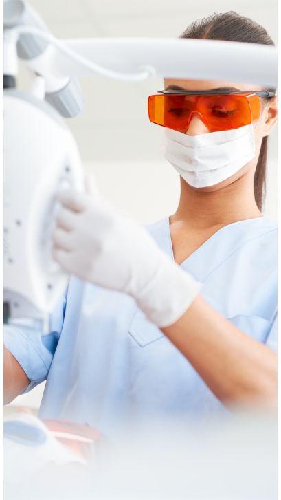 A dental professional adjusting a Philips Zoom! WhiteSpeed lamp