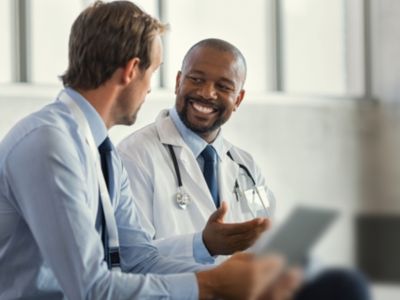 Doctor discussing patient information with colleague using digital device