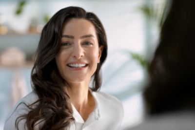Philips Sonicare elektrikli diş fırçasını kullanırken gülümseyen kadın