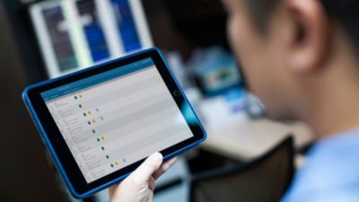 Un profesional médico revisa los datos del paciente en una tableta con el software de monitorización de pacientes de Philips