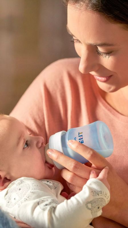 Junge Mutter füttert ihr Baby mit einer Philips Avent Flasche