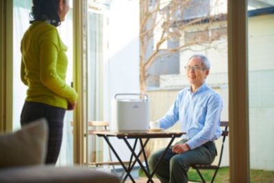 パティオでフィリップス SimplyGo コンセントレーターを使用している男性