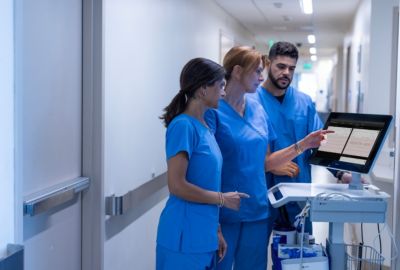 Clinicians reviewing patient data on a Philips patient monitoring workstation in a hospital corridor