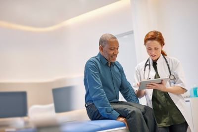 Doctor reviewing health data on tablet with patient in clinic