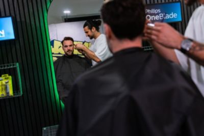 Friseur, der einen Kunden durch einen Spiegel sieht