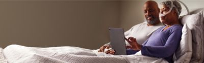  Couple in bed, woman looking at iPad 