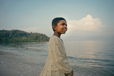 Niño de pie junto a la costa del mar