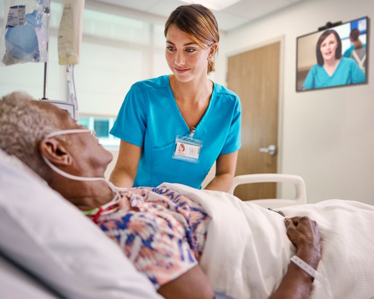 De verpleegkundige aan het bed en de virtuele verpleegkundige bieden zorg aan de patiënt.
