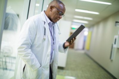 A doctor looking into a tablet in the hospital hallway