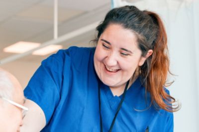 Medical professional in blue scrubs interacting with a patient in a clinical care environment