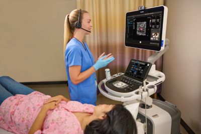 Physician in scrubs speaking to another physician virtually using Collaboration Live with patient on the bed