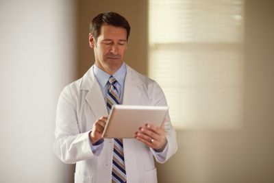 Clinician using digital tablet for reviewing patient data in medical setting