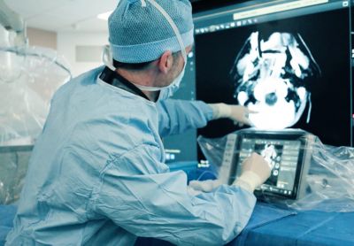 Interventional neuroradiologist working with a 3D-visualized brain scan during procedure