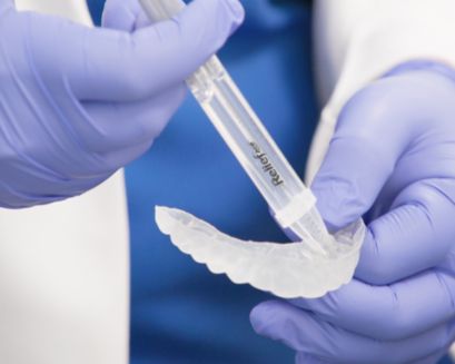 Hands applying Philips Relief ACP to a whitening tray.