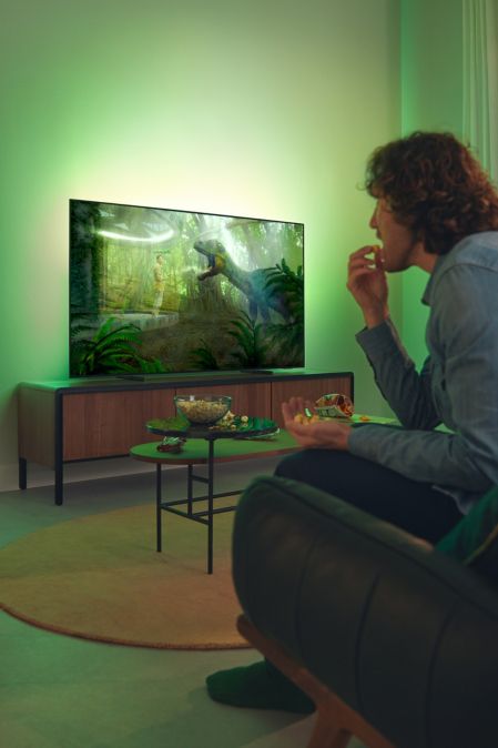 Philips Ambilight TV in a living room with two people watching.