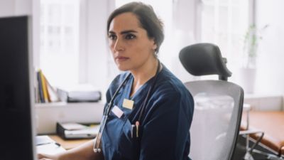 Profissional de saúde revisando informações do paciente no computador em consultório clínico