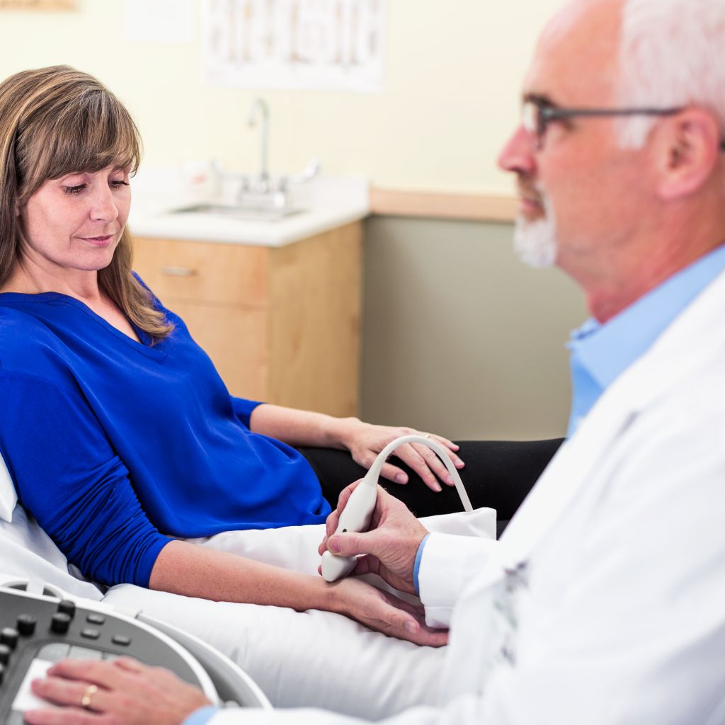 A patient receives an ultrasound exam on her wrist while her clinician interacts with the ultrasound system