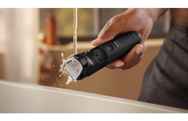 Product close-up of a Philips beard trimmer being cleaned under water.