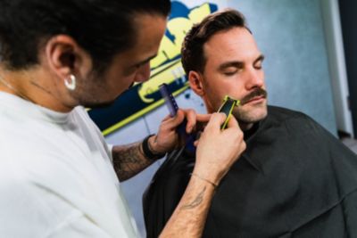 Friseur, der einen Schnurrbart mit einem elektrischen Trimmer trimmt