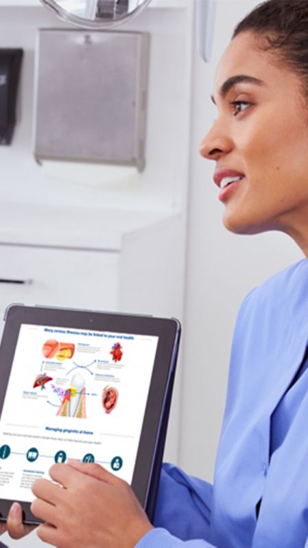 A dental professional holding the chairside guide converses with patient.