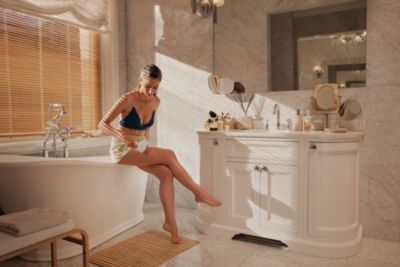 Erwachsener mit einem Haarentfernungsgerät am Bein im Badezimmer