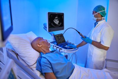 Un clínico realiza una ecocardiografía a pie de cama con un sistema Philips a un paciente monitorizado en una habitación de hospital