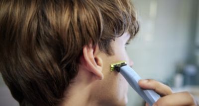 Person, die Haare hinter dem Ohr mit einem elektrischen Trimmer schneidet