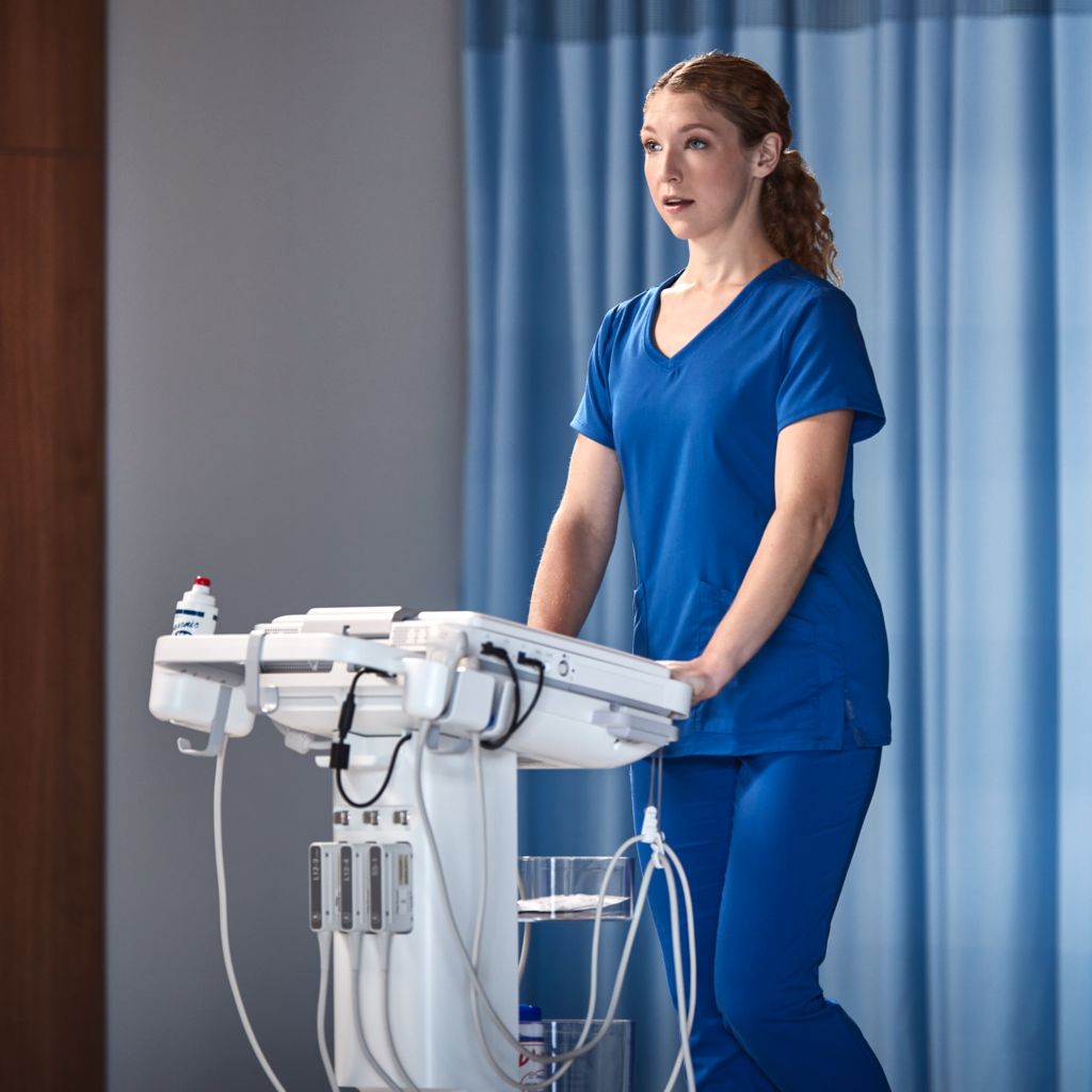 Photo of a female clinician remotely connecting with a specialist via teleultrasound from an ultrasound system while performing an ultrasound exam. 