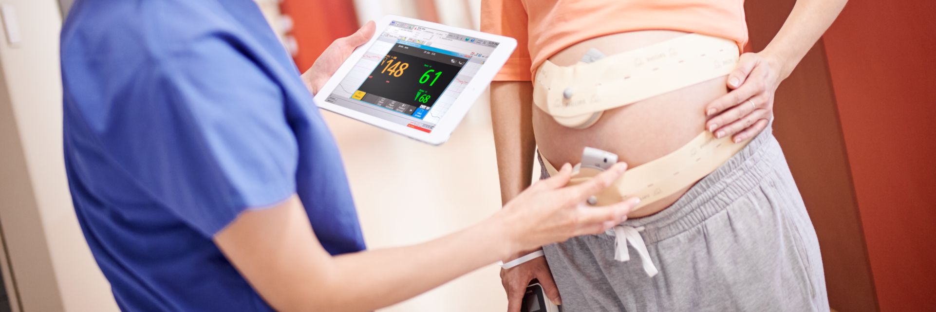 Pregnant patient wearing cableless solution with clinician adjusting a transducer